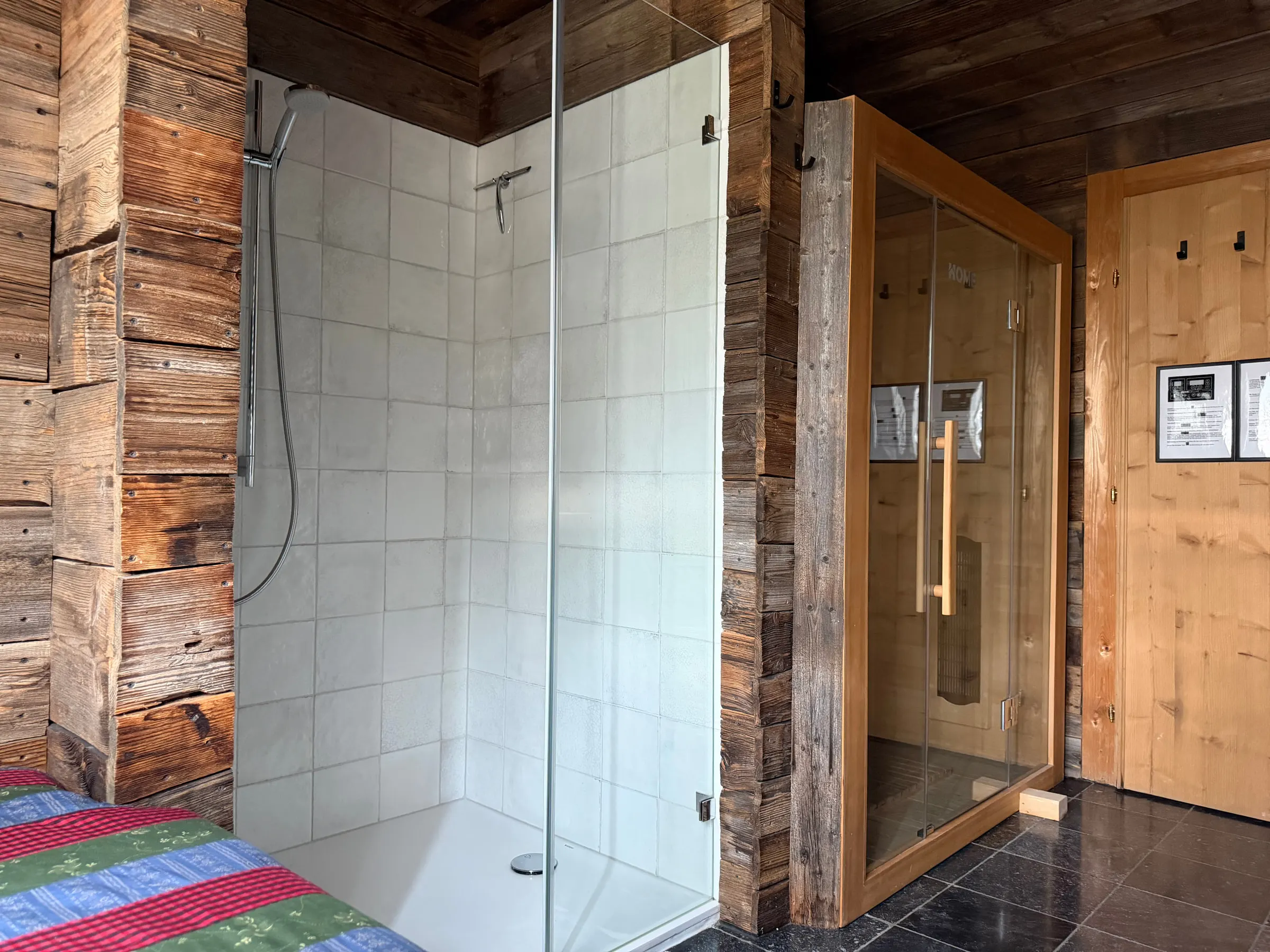 Bodengleiche Dusche mit Glaswand, daneben eine Infrarotkabine aus hellem Holz