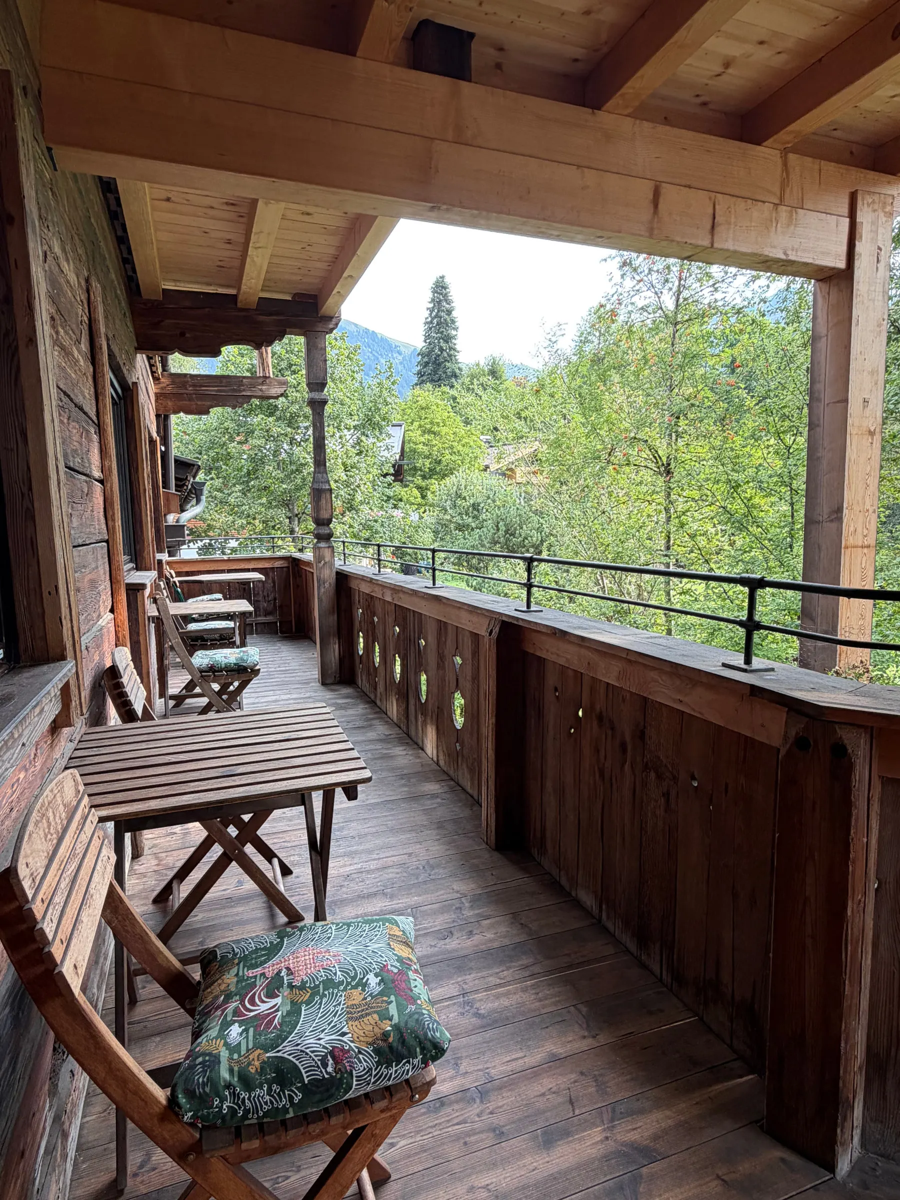 Balkon mit Blick ins Grüne, Bergkuppe zwischen den Bäumen
