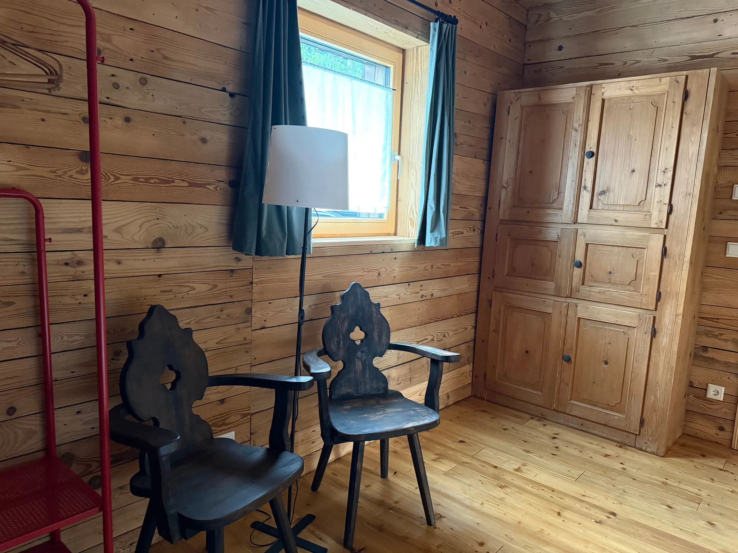 Sitzecke mit zwei alten Bauernstühlen, Stehlampe und Bauernschrank vor einem Fenster