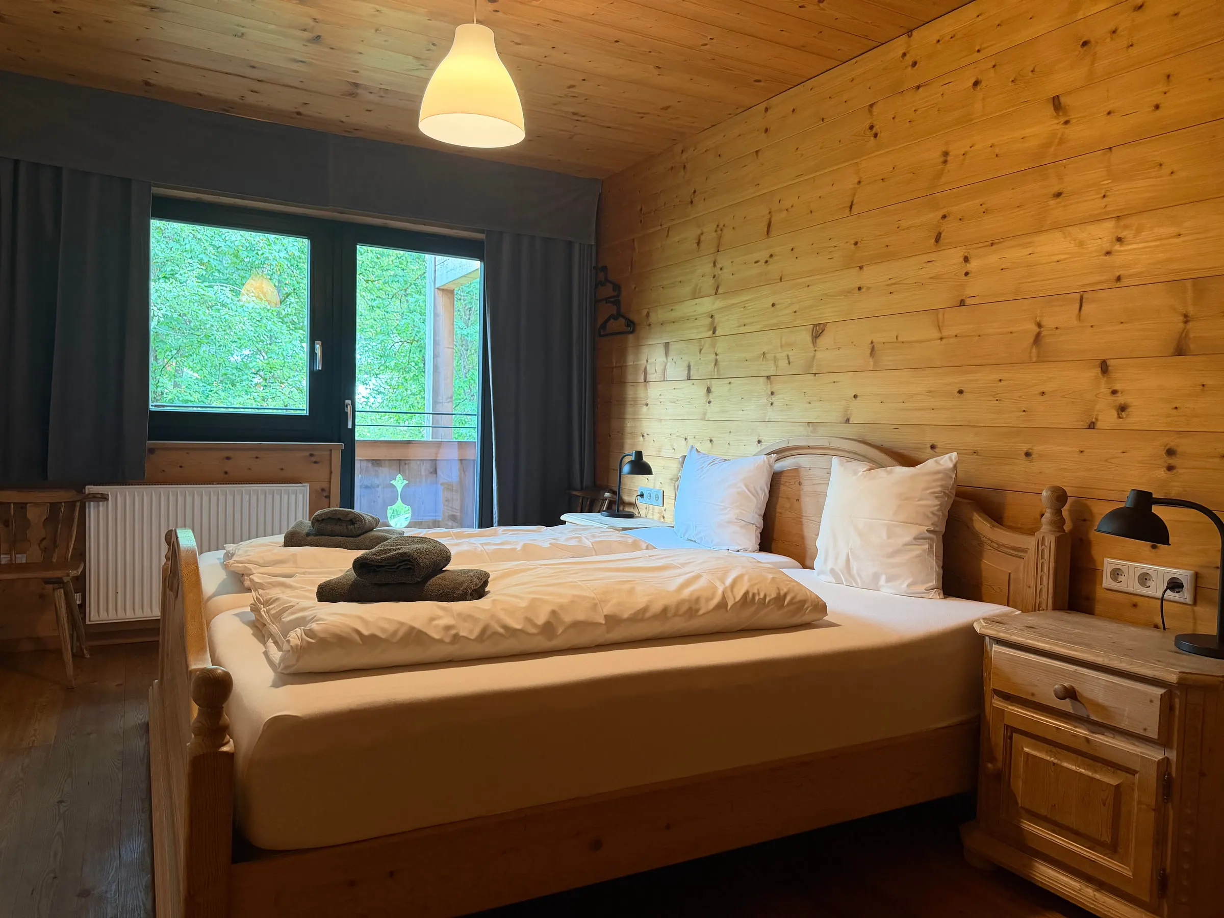 Dasselbe Schlafzimmer mit Balkontür, durch die man ins Grüne sieht